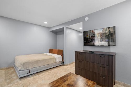a bedroom with a bed and a tv on a wall at Celebration Suites in Orlando