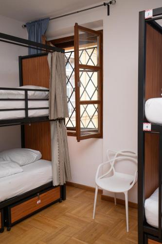 a bedroom with bunk beds with a chair and a window at Women's Only Hostel - Female Only in Prague