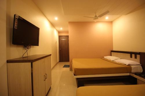 a small room with two beds and a flat screen tv at Hotel Sai Balaji in Shirdi