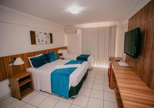 Schlafzimmer mit einem Bett und einem Flachbild-TV in der Unterkunft DiRoma Exclusive in Caldas Novas