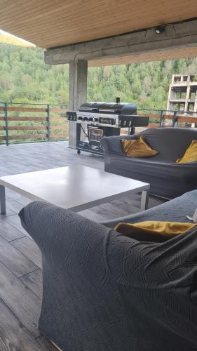 a patio with couches and a table and a grill at Mestia Roots in Mestia