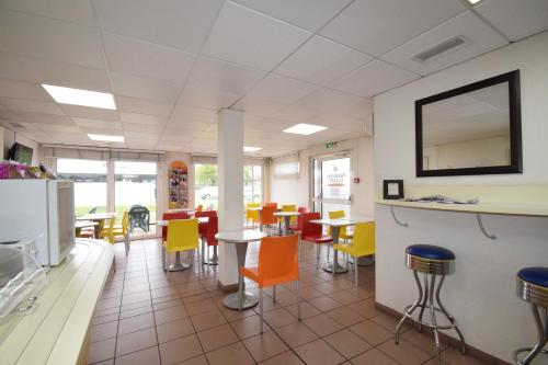 een eetkamer met kleurrijke stoelen en tafels bij Premiere Classe Bordeaux Sud Pessac Bersol in Pessac