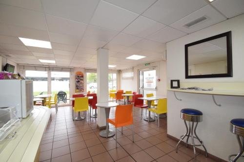 a dining room with colorful chairs and tables at Premiere Classe Bordeaux Sud Pessac Bersol in Pessac