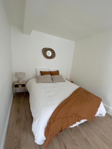 - une chambre avec un lit blanc et une couverture brune dans l'établissement Maisonnette à la campagne avec jardinet, à Ennery