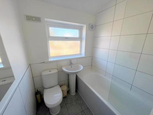 a white bathroom with a toilet and a sink at 4-Bedroom House - South London CR7 in Thornton Heath
