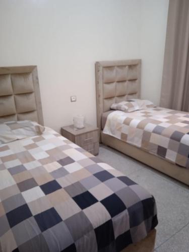 a bedroom with two beds and a night stand at Flat Al farabi in Agadir