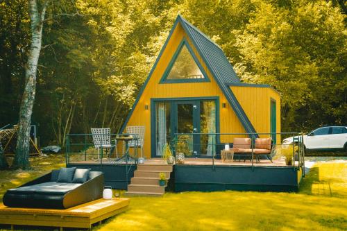 a small yellow house with a porch and a couch at Chata Auri / Hütte Auri in Kaplice