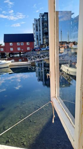 una ventana con vistas a un puerto deportivo con barcos en el agua en Det kule gule huset en Svolvær