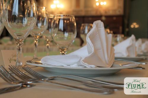 a table with silverware and wine glasses on a table at Fiume Hotel in Békéscsaba