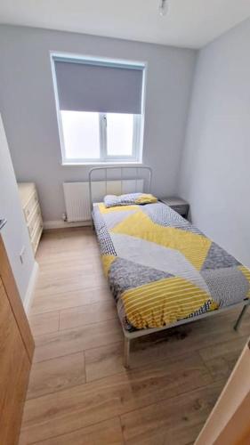 een slaapkamer met een bed met gele en grijze lakens bij Modern 2-bedroom flat in South London in Sutton