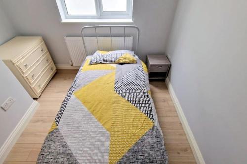 een slaapkamer met een bed met een gele en grijze deken bij Modern 2-bedroom flat in South London in Sutton