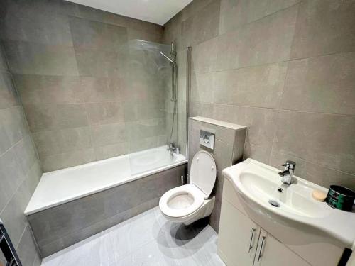 een badkamer met een toilet, een wastafel en een bad bij Modern 2-bedroom flat in South London in Sutton