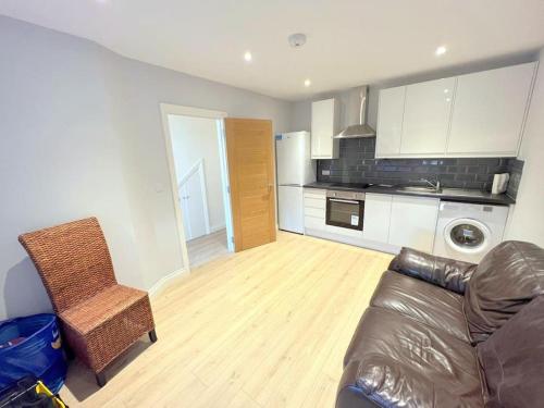 een woonkamer met een bank en een keuken bij Modern 2-bedroom flat in South London in Sutton