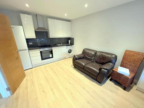 a living room with a leather couch and a kitchen at Modern 2-bedroom flat in South London in Sutton