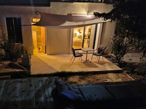 a patio at night with a table and chairs at Mas L'Escale des Dentelles in Aubignan
