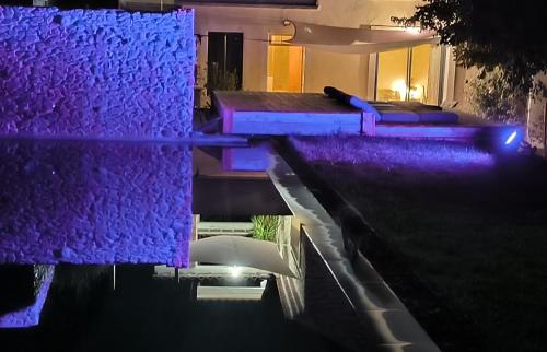 a house with purple lights on the water at night at Mas L'Escale des Dentelles in Aubignan