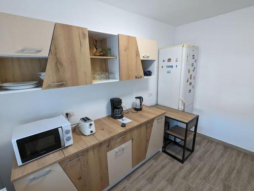 a kitchen with a counter with a microwave and a refrigerator at Cozy Modern Apartment Km 0 Craiova in Craiova