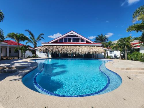 una piscina frente a un complejo con techo de paja en Ceiba Beach Resort, en Maya Beach