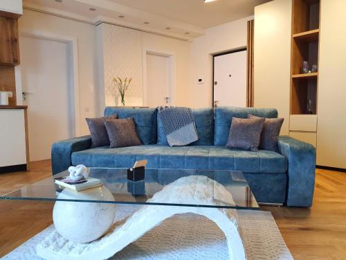 a blue couch in a living room with a glass table at Lavish Inn Apartment in Cluj-Napoca