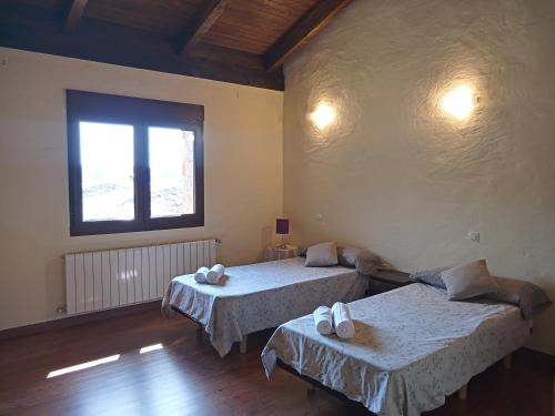 Luelmo的住宿－Casa Rural Alada，客房设有两张床和窗户。