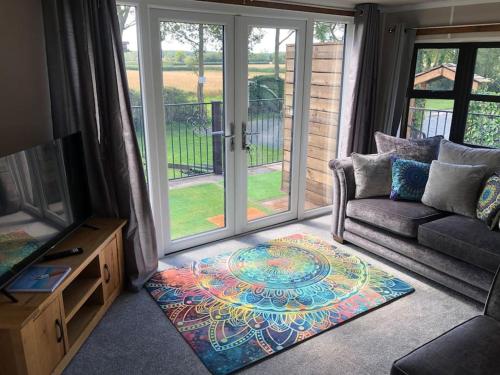 a living room with a couch and a glass door at Couple’s Lodge With Hot Tub in Lincolnshire