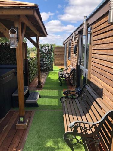 a porch with two benches and a house at Couple’s Lodge With Hot Tub in Lincolnshire