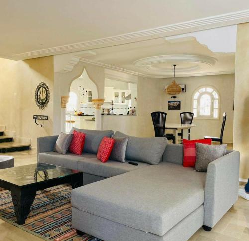 a living room with a gray couch and red pillows at Mille & une nuit in Al Maqārisah