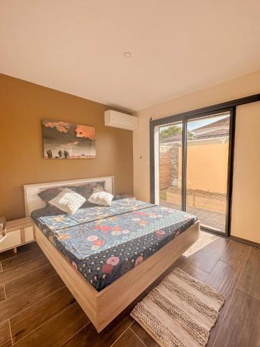 a bedroom with a bed and a large window at Les Villas Jasmin Standing Piscine Chauffée Jacuzzi 5 Ch 14 Pers in Baie-Mahault