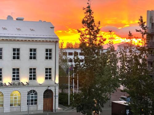a sunset in a city with a white building at Lovely Penthouse downtown with 3 bedrooms in Akureyri