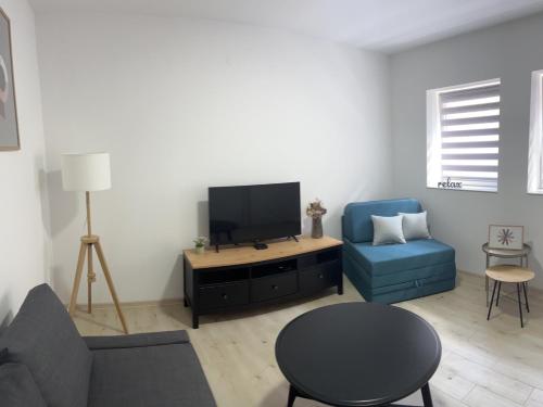 - un salon avec une télévision et une chaise bleue dans l'établissement New studio apartment with separate kitchen in center of Ruma, à Ruma