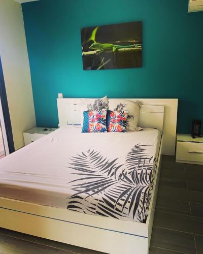 a bedroom with a white bed with a blue wall at Les Villas Jasmin Standing Piscine Chauffée Jacuzzi 5 Ch 14 Pers in Baie-Mahault