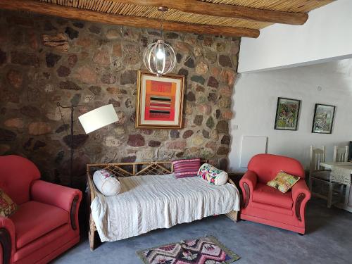 a bedroom with a bed and two red chairs at El Cobijo del Artista - en Huacalera in Huacalera