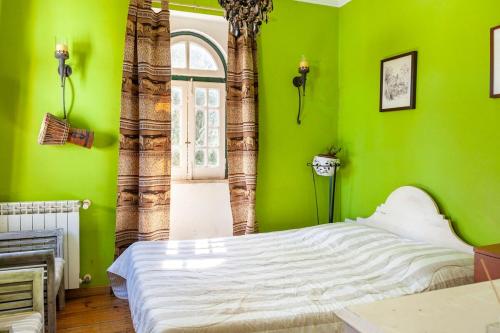 a bedroom with green walls and a white bed at B&B Quarto Verde Estilo Africano in Ramalhal