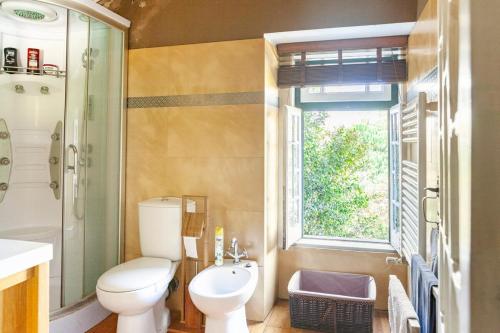 a bathroom with a toilet and a shower and a window at B&B Quarto Verde Estilo Africano in Ramalhal
