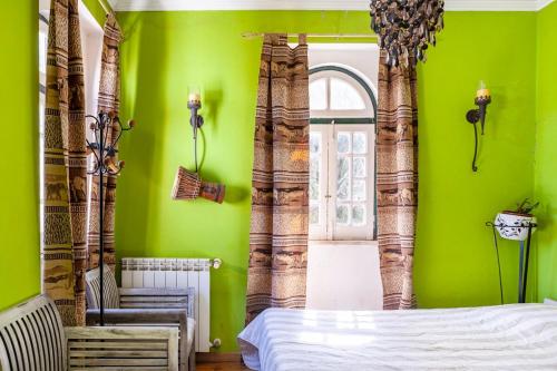 a bedroom with green walls and a bed and a window at B&B Quarto Verde Estilo Africano in Ramalhal