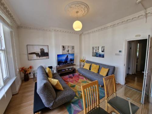 een woonkamer met 2 banken en een tv bij Beautiful Kensington Home by Earl's Court Station in Londen