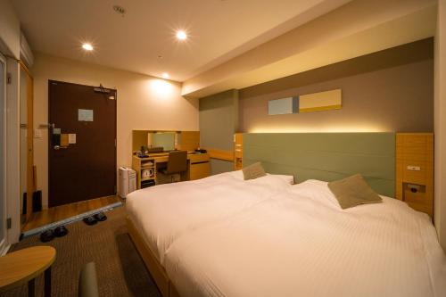 a bedroom with a large white bed and a desk at Super Hotel Premier Tokyo Station Yaesu-Chuoguchi in Tokyo