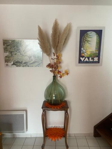 a green vase sitting on a table with flowers in it at La Cigale Ardéchoise in Labégude