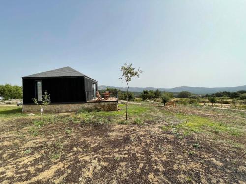 a small black building in a field with a tree at Casa Otea in Avila