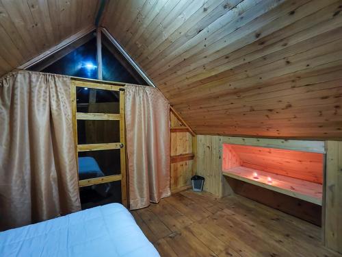 Habitación de madera con cama y ventana en Maeponecoturismo, en Gámeza