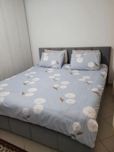 a bed with a blue blanket with white flowers on it at Brayan guest house in Pogradec