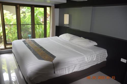 1 dormitorio con 1 cama grande con sábanas blancas y ventanas en Kalim Residence, en Patong Beach