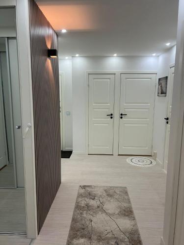 a hallway with white doors and a rug at Rum i lyxig lägenhet nära Emporia in Malmö