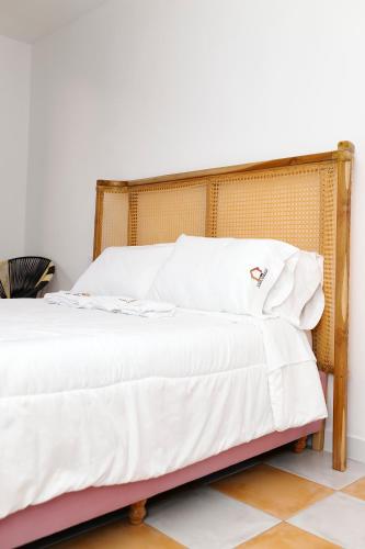a bed with white sheets and a wooden headboard at Hostal Casa Torres Centro Historico - Adults Only in Cartagena de Indias