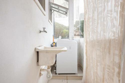 a white bathroom with a sink and a window at LOFT Luz Solar Buzios in Búzios