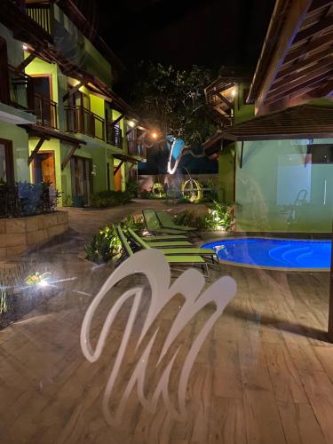 una señal de hotel frente a una piscina por la noche en The Madalena Pousada en Imbassai