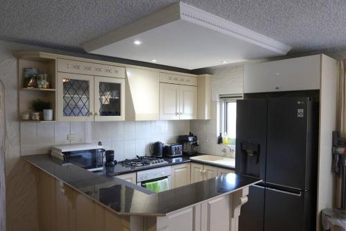 a kitchen with white cabinets and a black refrigerator at Sunsets At Glenelg in Glenelg