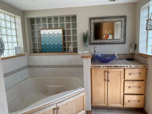 ein Badezimmer mit einer Badewanne, einem Waschbecken und einem Spiegel in der Unterkunft Surfside Shangri La in Daytona Beach