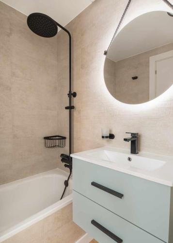 a bathroom with a sink and a mirror and a tub at Elurra II Confort in Formigal