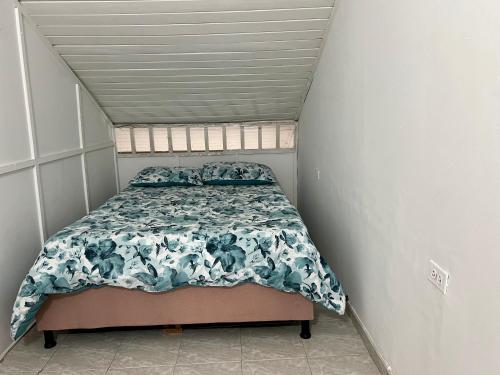 Dormitorio pequeño con cama con edredón azul y blanco en Maja Hospedaje Apartamento con aire frente al Mar en Cartagena de Indias
